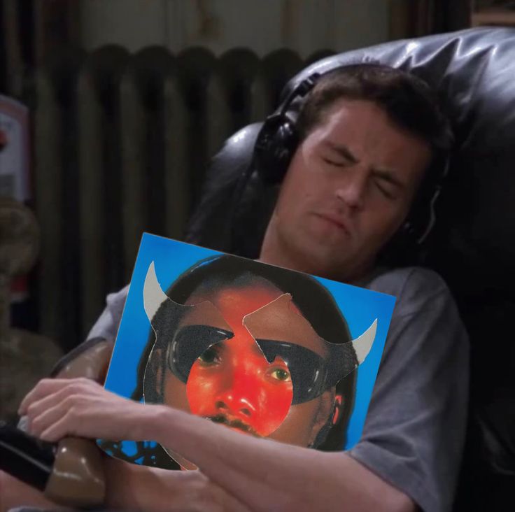 a man laying in a chair with his head resting on a pillow while holding a book