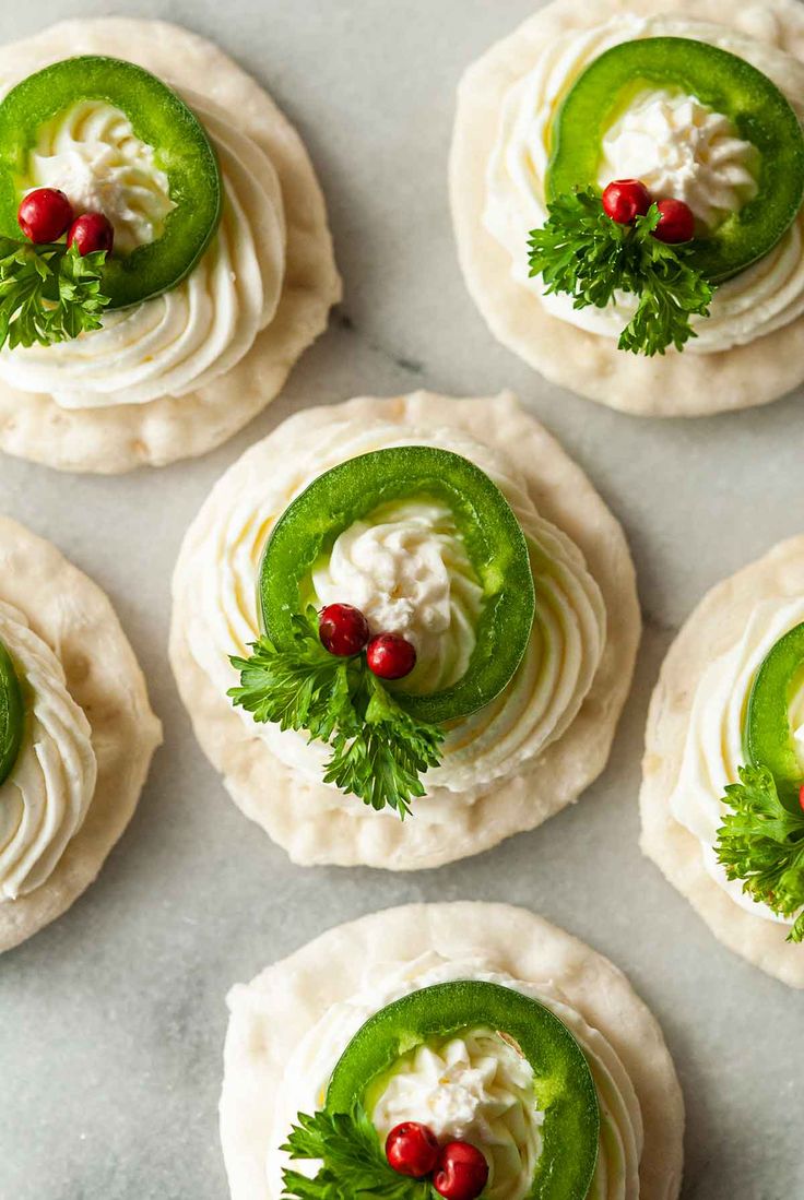 six small green and white desserts with red berries on the top one is topped with cream cheese