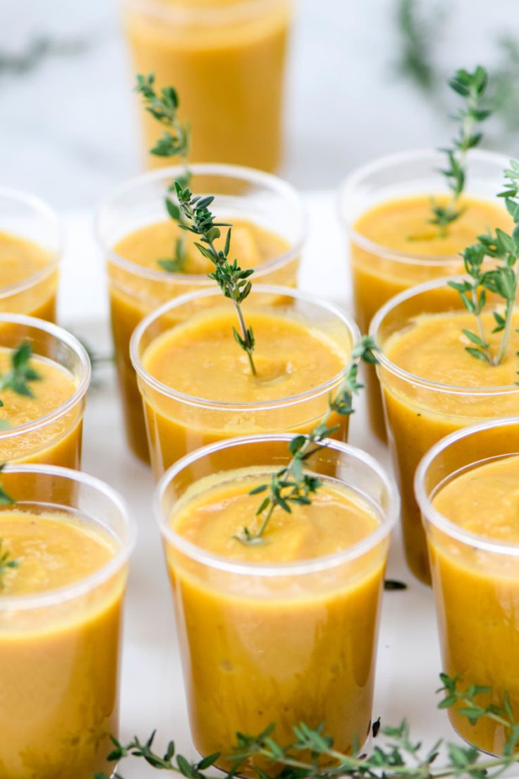 small cups filled with yellow liquid and garnished with greenery