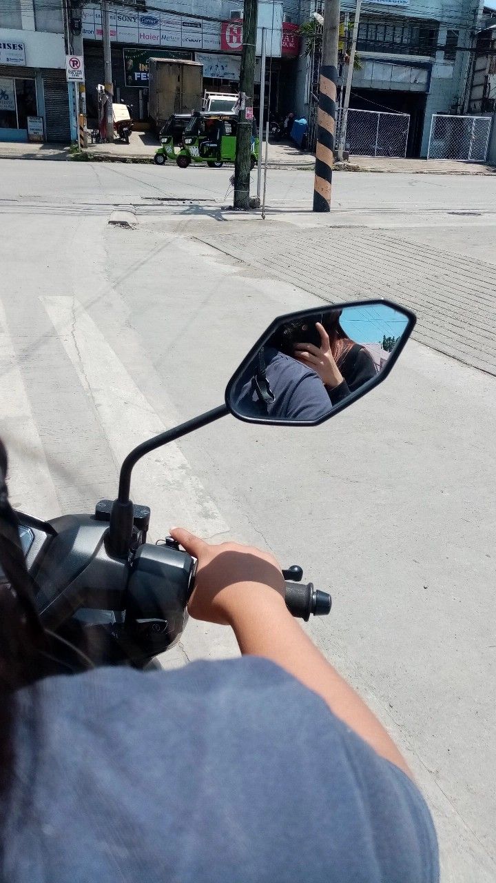 a person on a motorcycle taking a photo in the side mirror