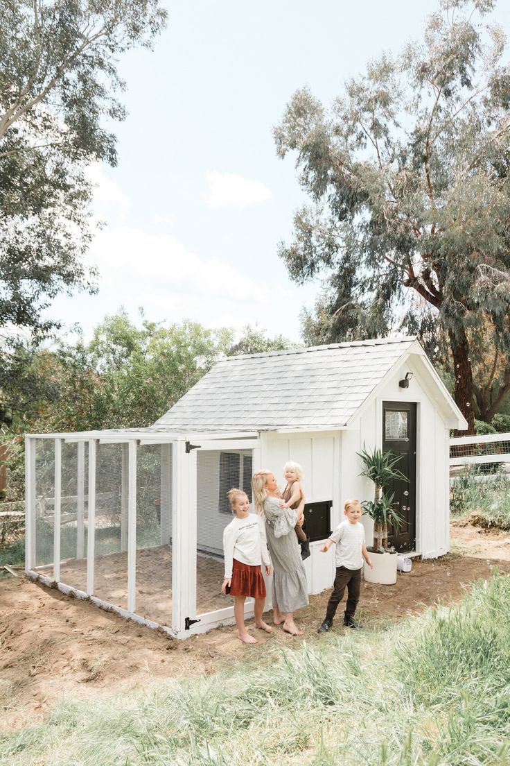 three children are standing in front of a chicken coop that is built into the ground