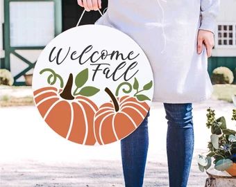 a woman holding a sign that says welcome fall