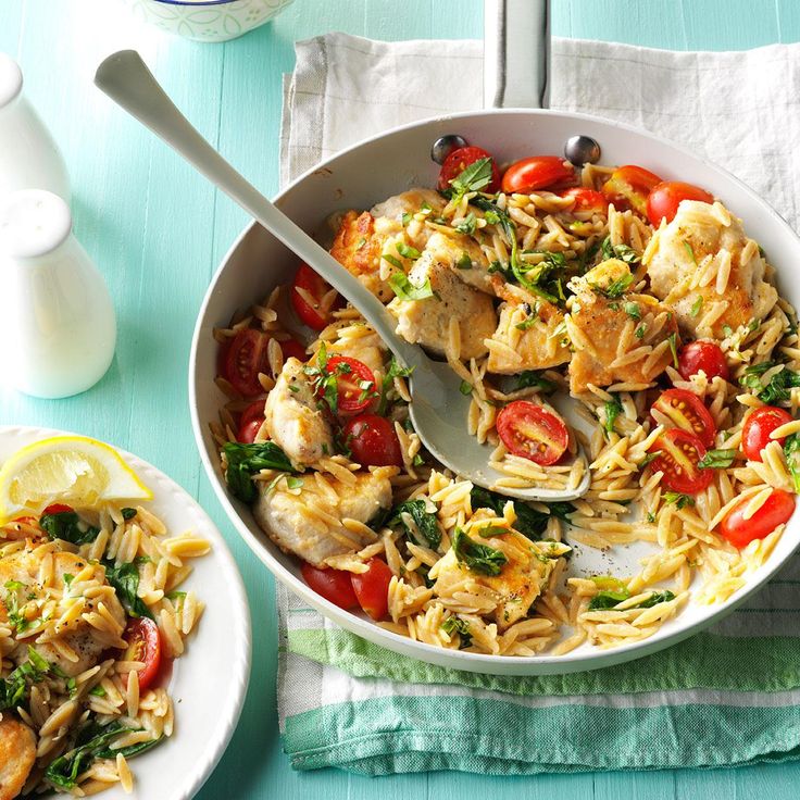 a pan filled with pasta and vegetables on top of a blue table cloth next to a bottle of milk