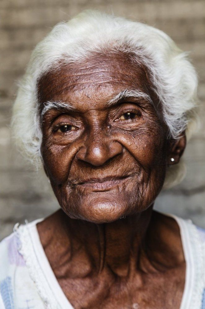 an old woman with white hair and wrinkles on her face, looking at the camera