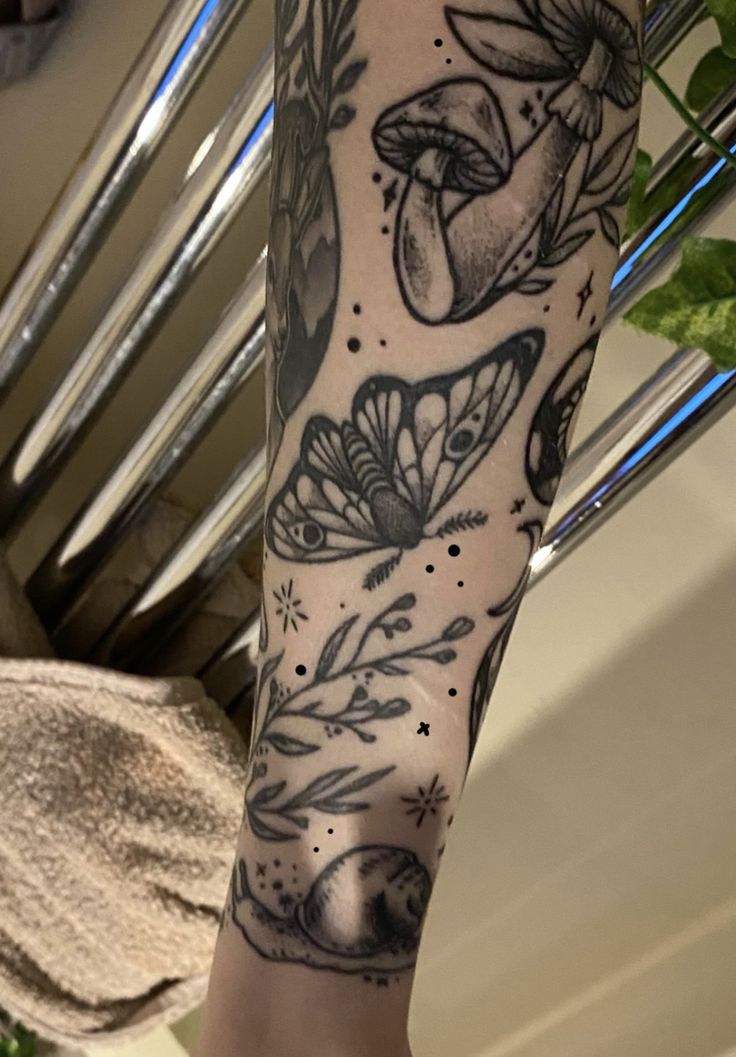 a woman's leg with tattoos on it and flowers in the background, including mushrooms