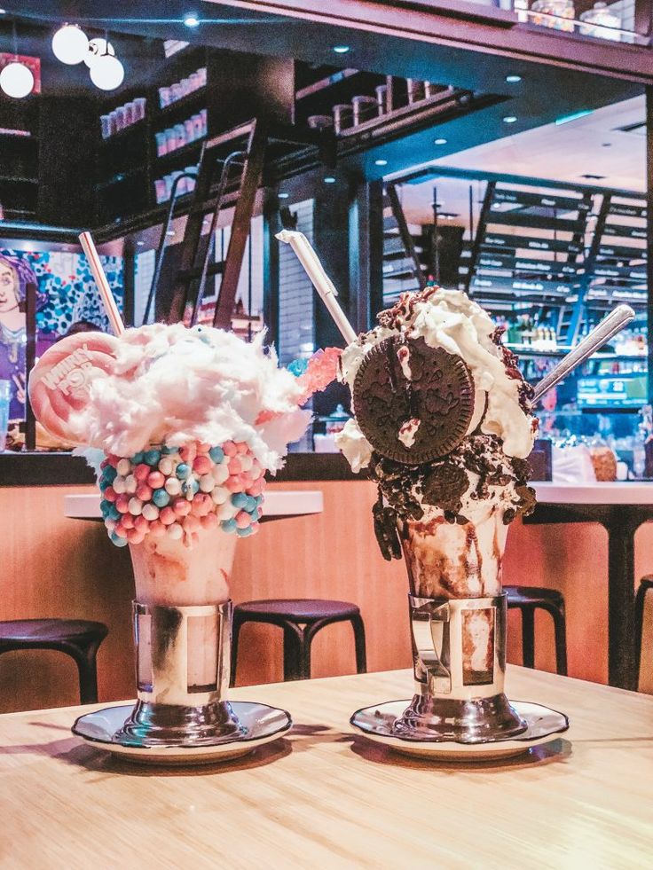 two ice cream sundaes sitting on top of a wooden table