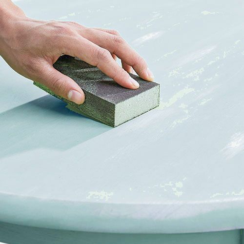 a person cleaning a table with a sponge