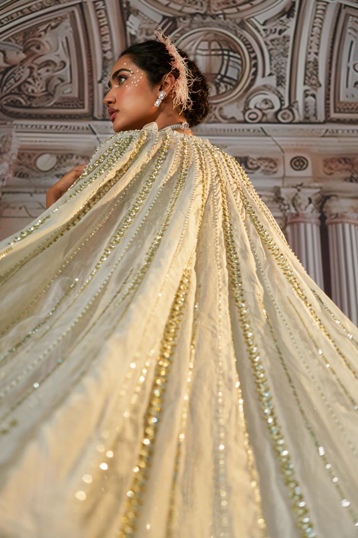 Step into elegance with this stunning georgette lehenga, showcasing symmetrical and exquisite embroidery that captures attention. Enhanced with sequins and beads, the design is beautifully defined, adding a touch of sophistication. The outfit features a long tail cape (optional) adorned with intricate embroidery and detailed feathers, elevating the overall look with a dramatic flair. Completing this enchanting ensemble is an embroidered dupatta that perfectly complements the lehenga, making it a perfect choice for special occasions where you want to leave a lasting impression. Embroidered Drapes, Fishtail Lehenga, Silver Lehenga, Grey Lehenga, Tuxedo Accessories, Georgette Lehenga, Beach Wedding Guests, Long Cape, Gown Skirt