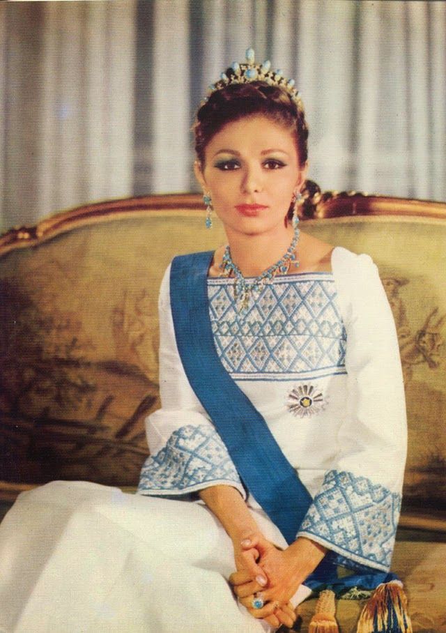 a woman sitting on top of a couch wearing a blue and white dress with a tiara