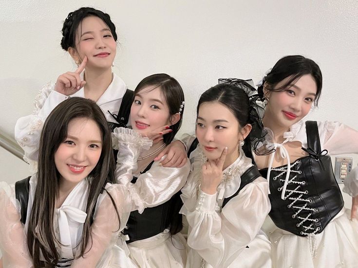 four young women dressed in white and black posing for the camera with their hands on their hips