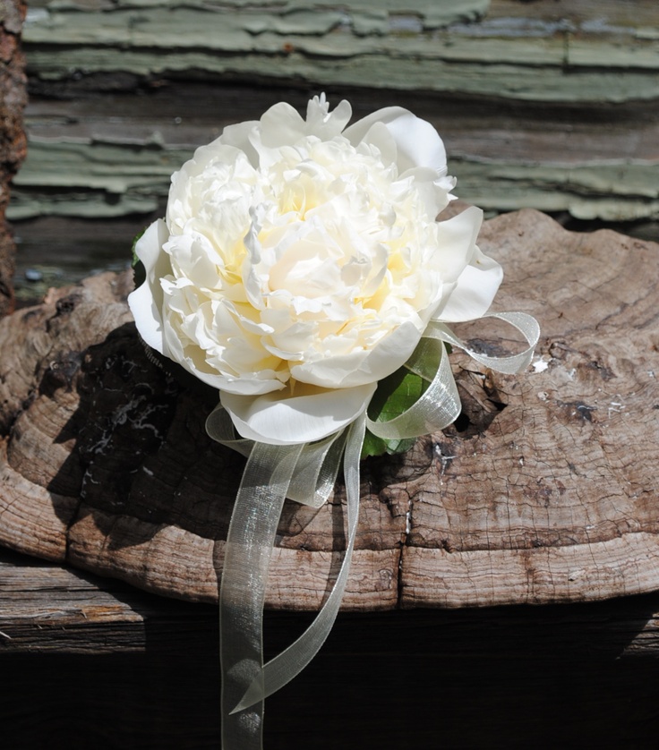 a large white flower sitting on top of a piece of wood next to a ribbon