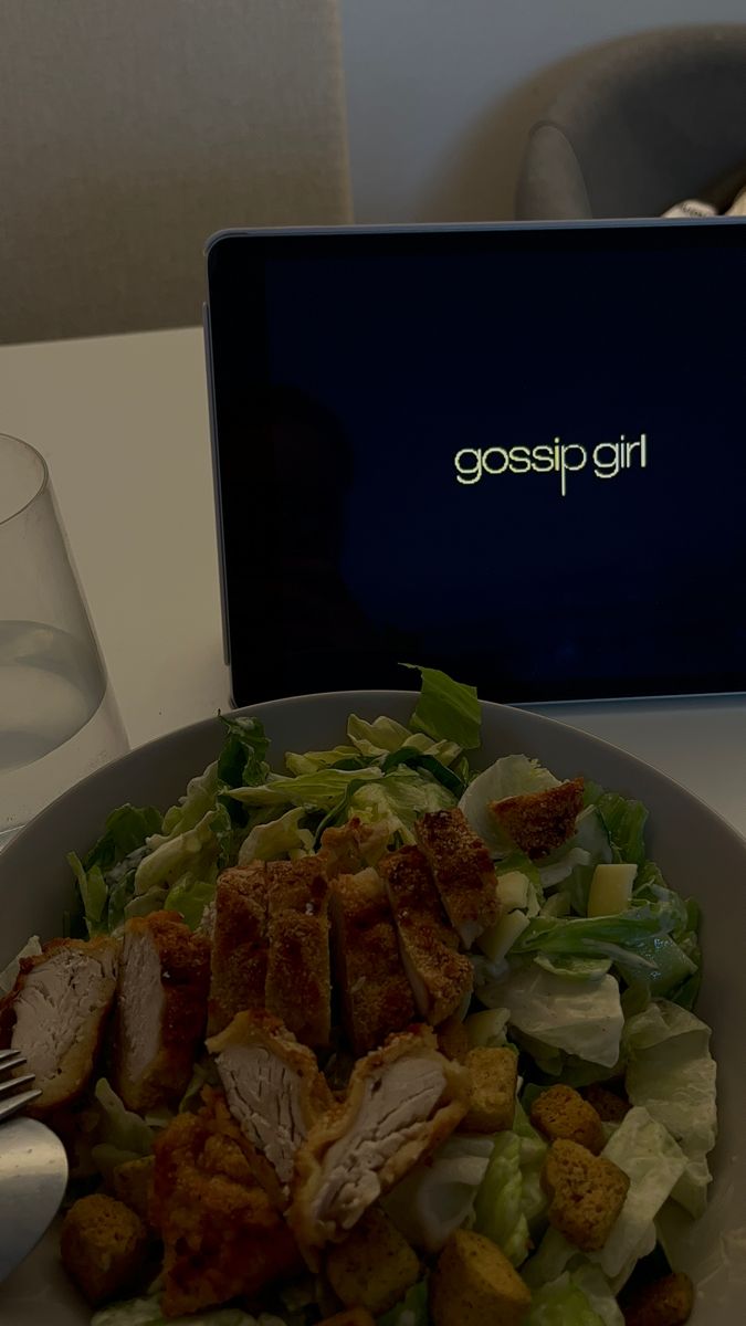 a white plate topped with salad next to a laptop computer