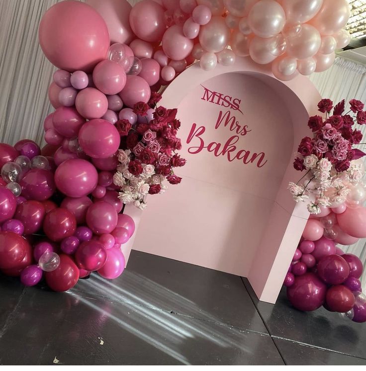 the balloon arch is decorated with pink and white balloons