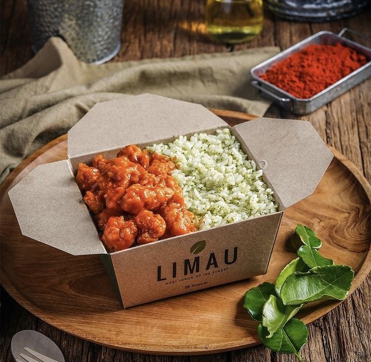 an open box of food sitting on top of a wooden plate next to some spices