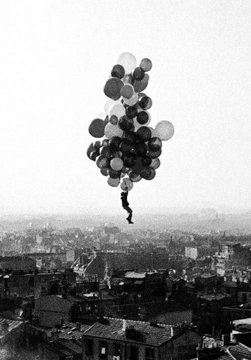 a bunch of balloons floating in the air over a city