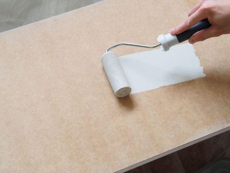 a person using a paint roller on a piece of cardboard with a roll of white paper