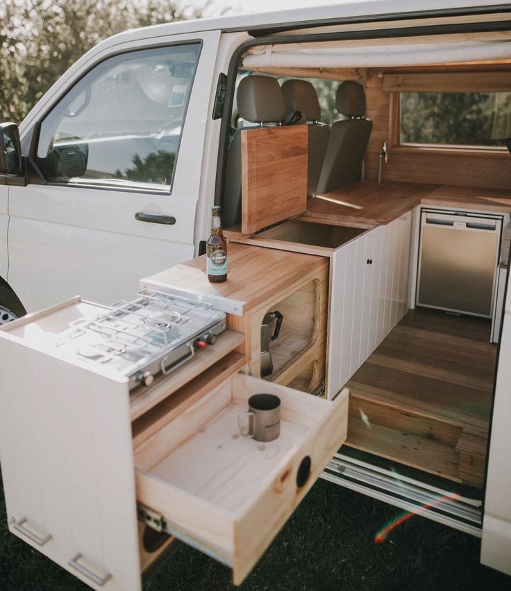 the interior of a camper van with its door open and drawers pulled out to allow extra storage