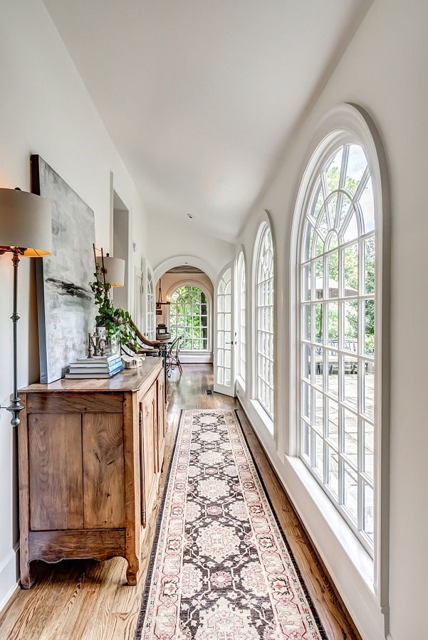 a large hallway with arched windows and a rug on the floor in front of it