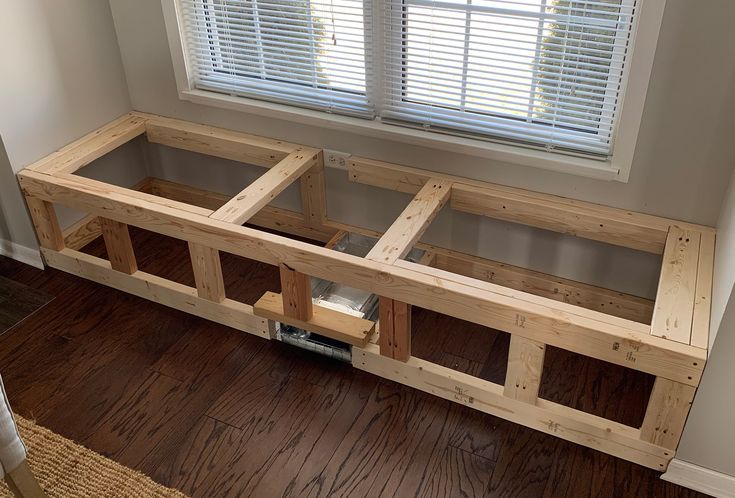 a wooden bench sitting in front of a window on top of a hard wood floor