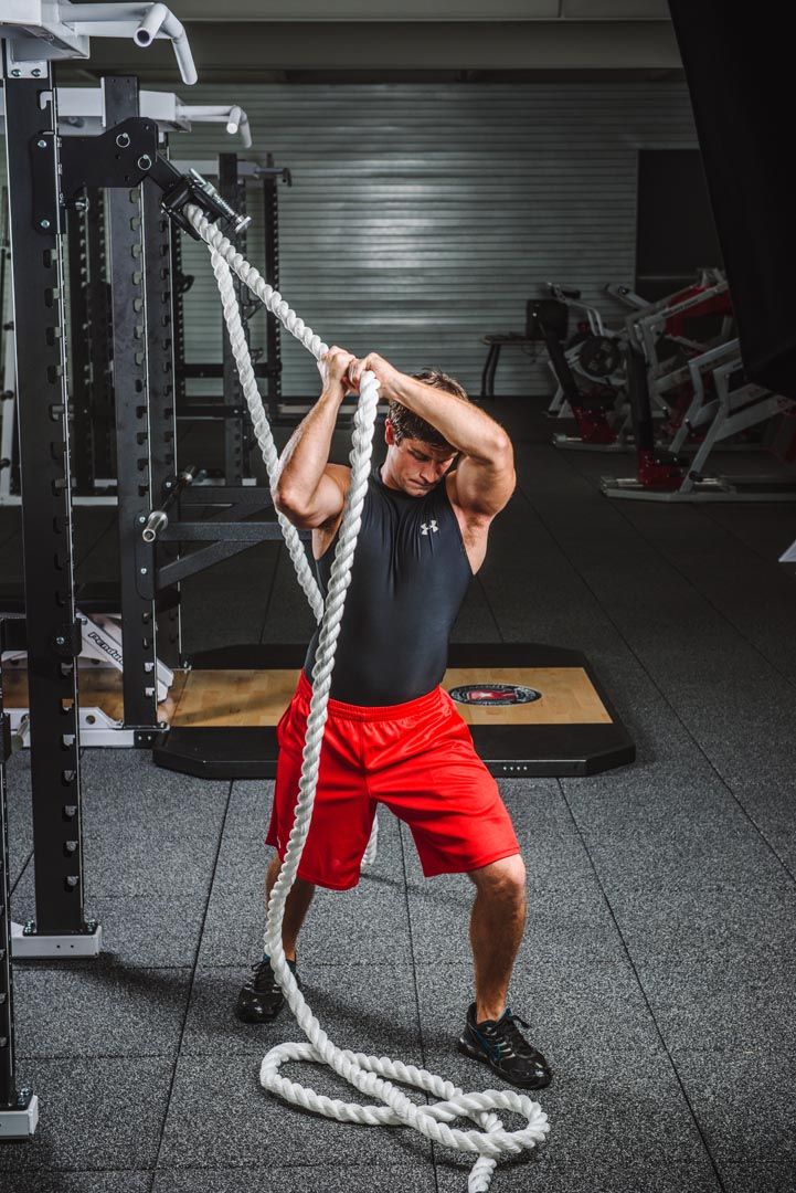 a man is doing pull ups with ropes in the gym, while holding his hands behind his head