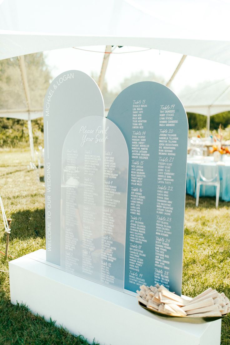 a couple of white tombstones sitting on top of a grass covered field next to a table