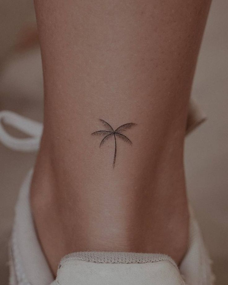 a small palm tree tattoo on the back of a woman's leg, which is shown above her left ankle