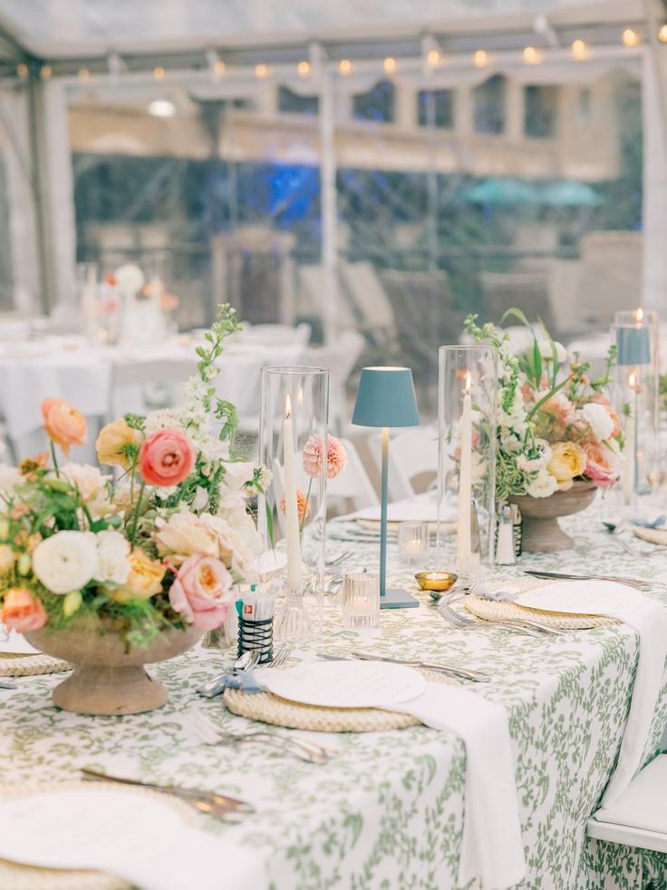 the table is set with flowers, candles and place settings for an elegant wedding reception