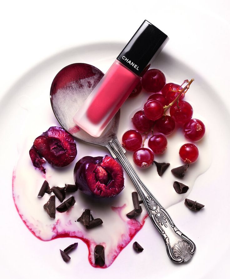 a white plate topped with cherries and chocolate chips next to a spoon filled with liquid