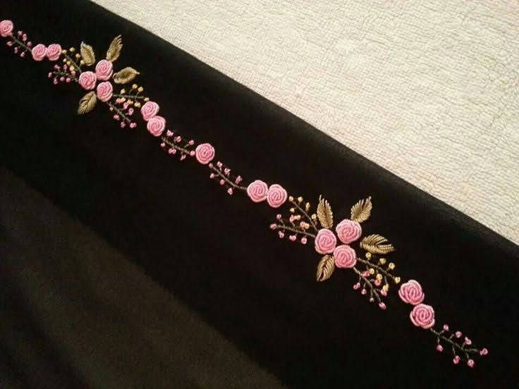 a black table cloth with pink flowers and leaves embroidered on the side, along with white linen