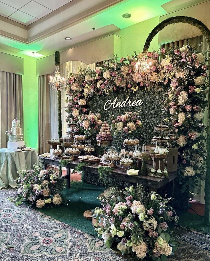 a table topped with lots of flowers next to a wall filled with cakes and desserts