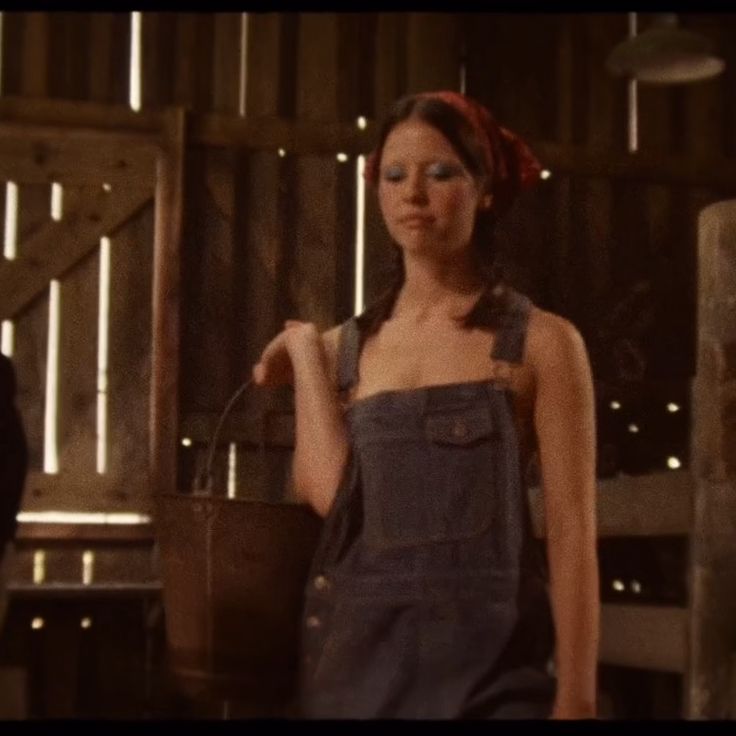 a woman in overalls holding a bucket