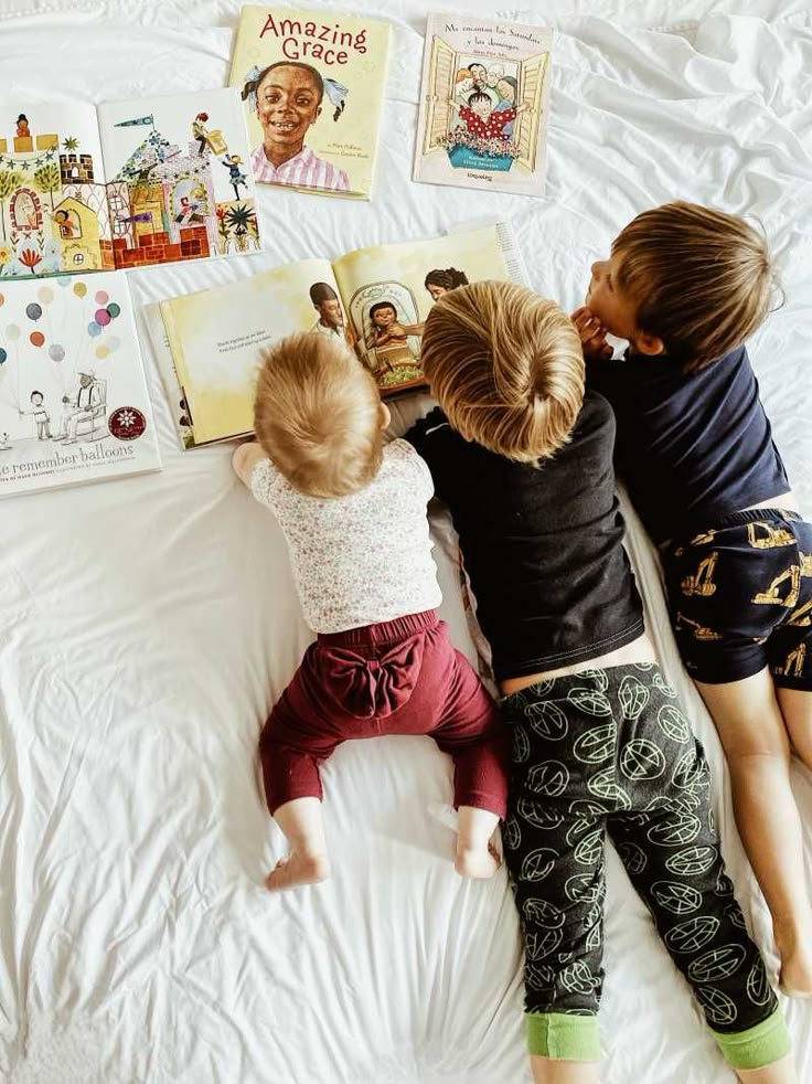 two children laying on a bed reading books