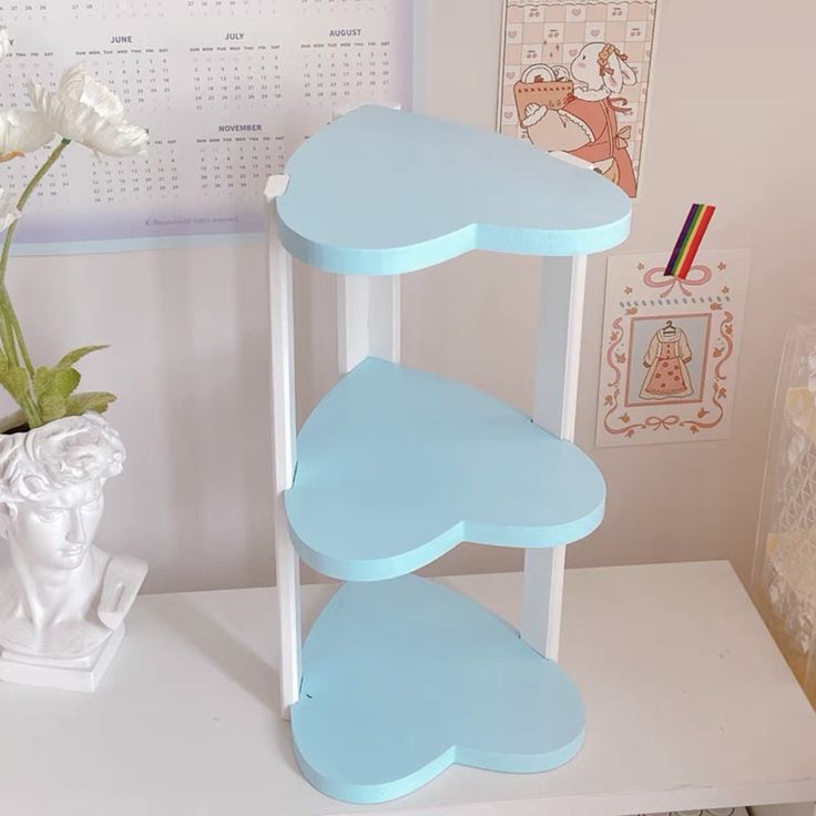 a three tiered shelf next to a vase with flowers