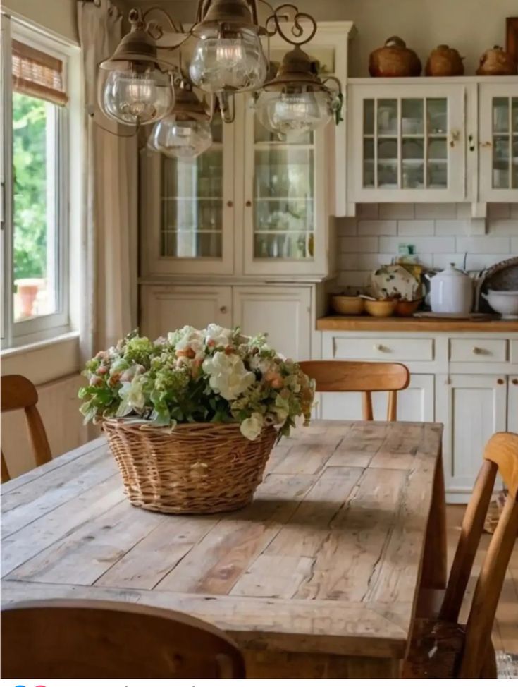 a wooden table topped with a basket filled with flowers next to a kitchen counter top