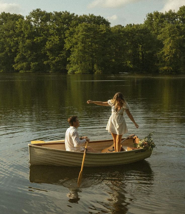 two people in a small boat on the water, one pointing at another person's hand