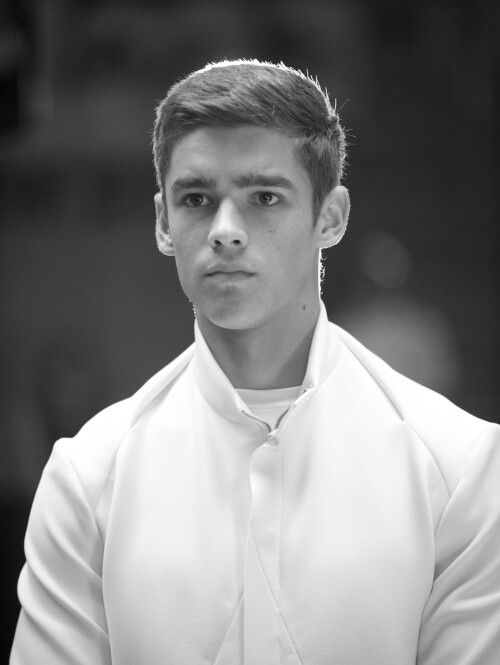 black and white photograph of a young man wearing a collared shirt with his hands in his pockets