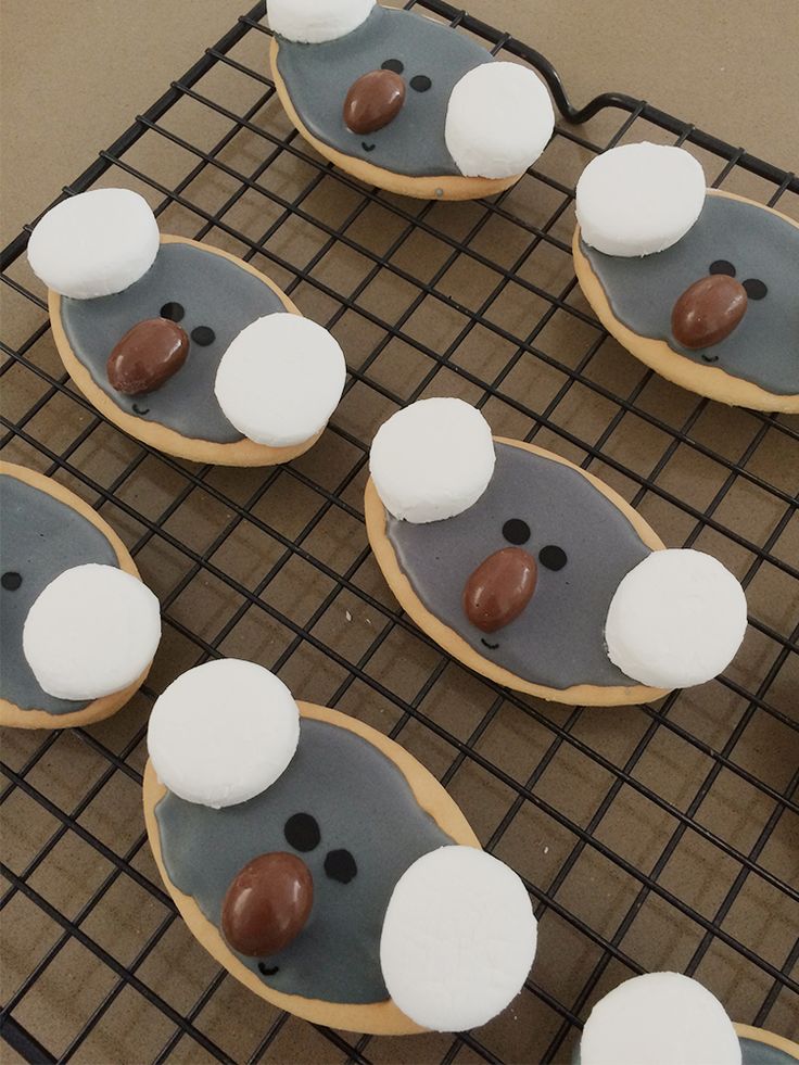 cookies decorated to look like penguins on a cooling rack with white and brown frosting