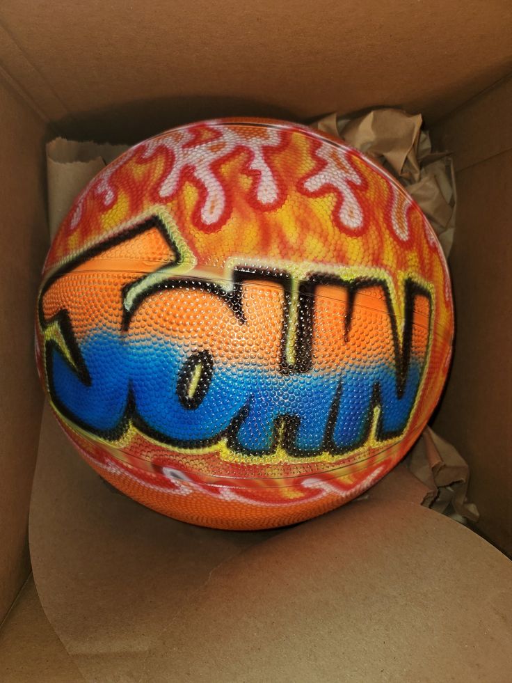 an orange and blue ball with the word wow painted on it in a cardboard box