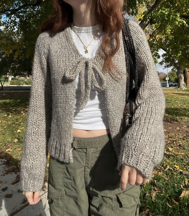 a woman with red hair wearing green pants and a sweater