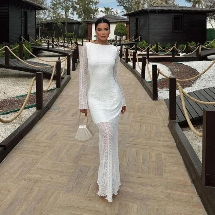 a woman in a white dress walking down a wooden walkway