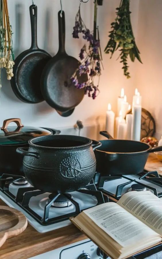 an open book sitting on top of a stove next to two pots and pans