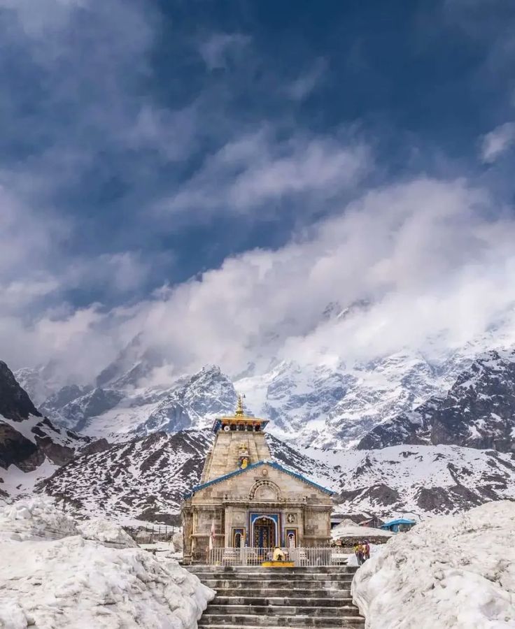 a small building with steps leading up to it in the middle of snow covered mountains