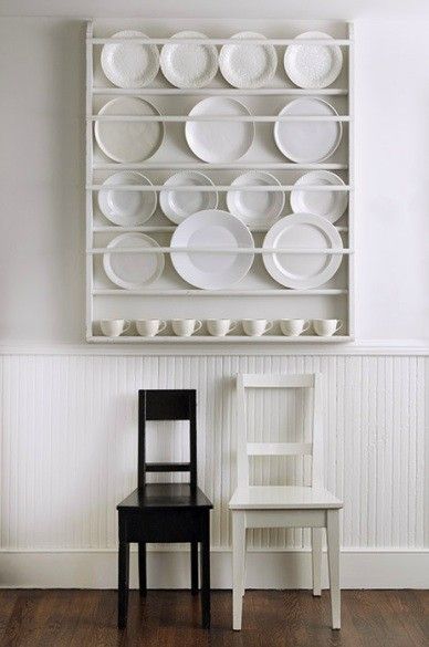 two chairs sitting next to each other in front of a shelf with plates on it