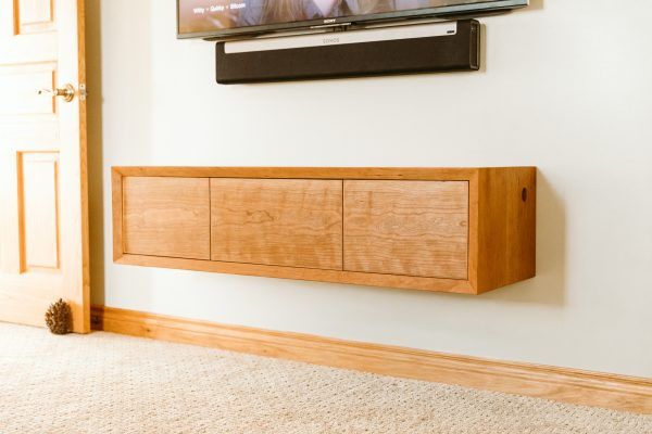 a flat screen tv mounted to the side of a wall next to a wooden cabinet