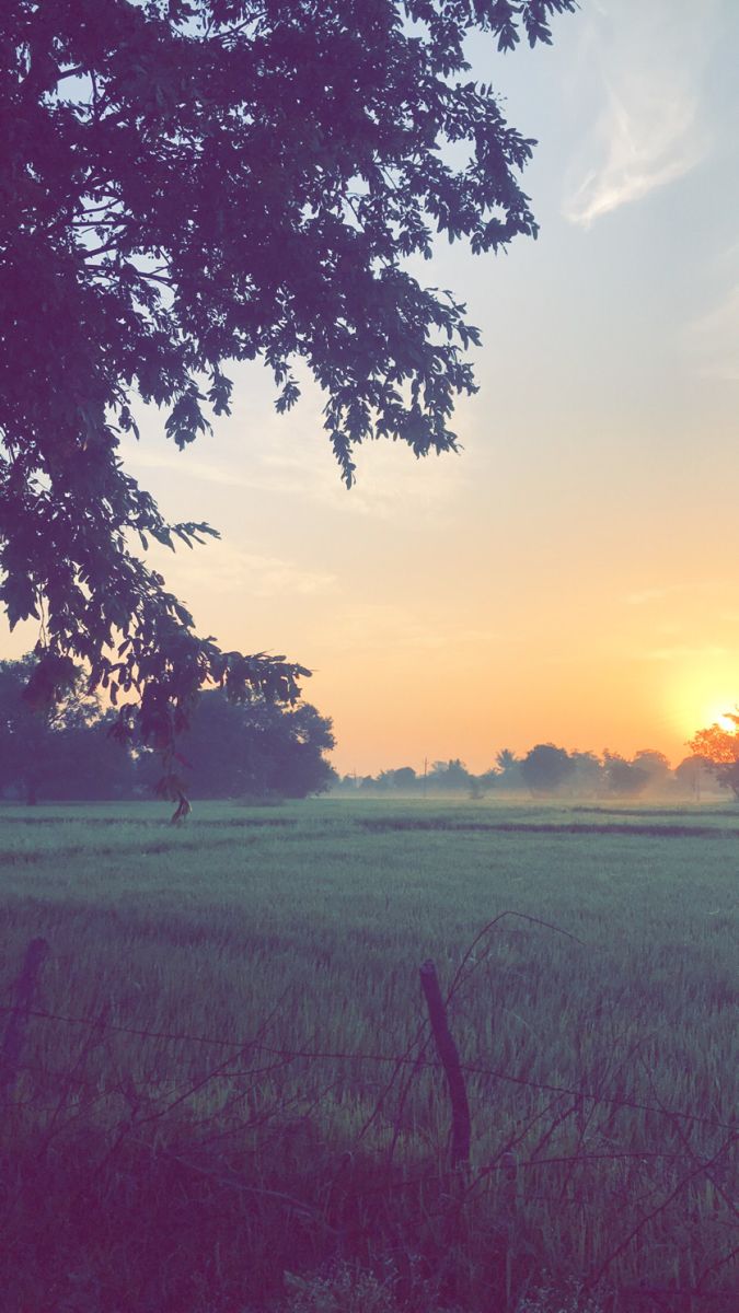 the sun is setting over an open field