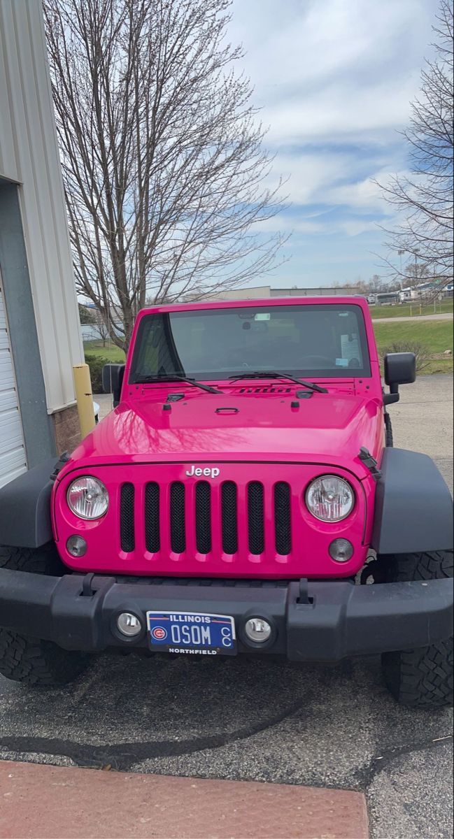 a bright pink jeep parked in front of a building with no one on it's roof