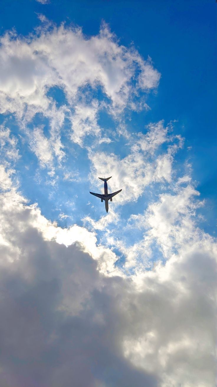 an airplane is flying in the sky with some clouds behind it and blue skies above