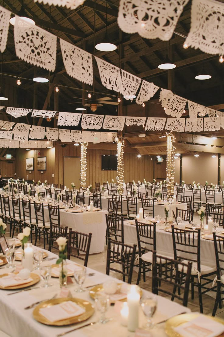 tables and chairs are set up for a wedding reception with white tablecloths, lace doily hanging from the ceiling