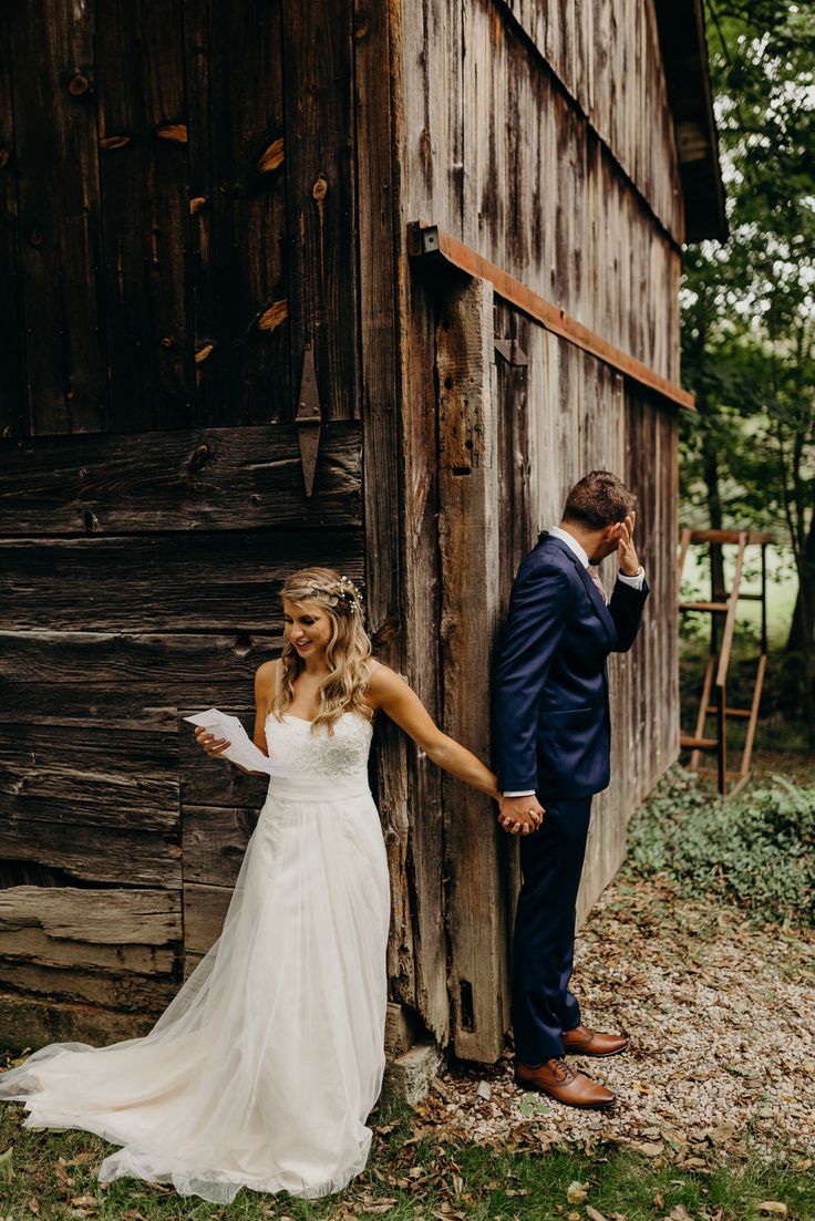 a bride and groom holding hands in front of a rustic barn with an old wooden door