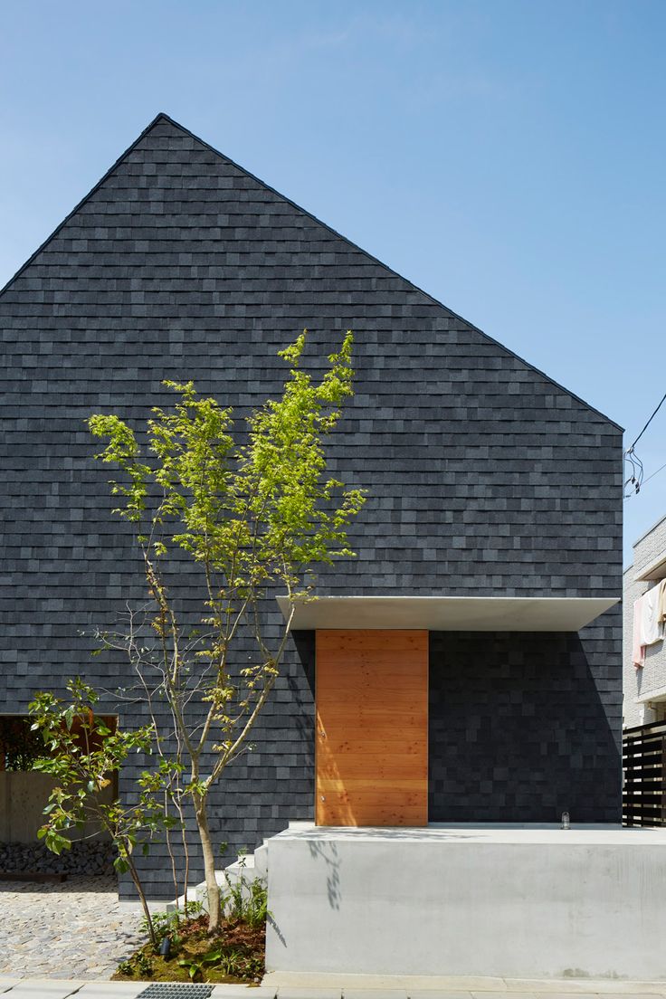 the house is made out of black shingles and has a wooden door on one side